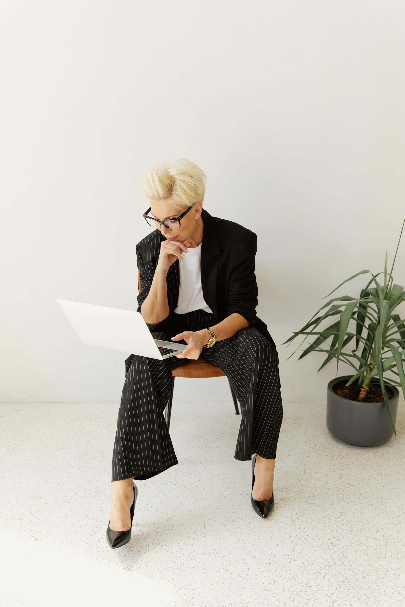 Professional woman in business attire working on laptop indoors, displaying focus and style.