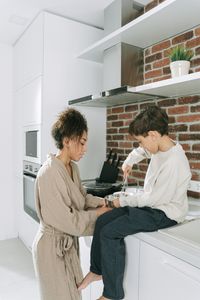 A mother and son enjoying quality time cooking in a contemporary kitchen setting.