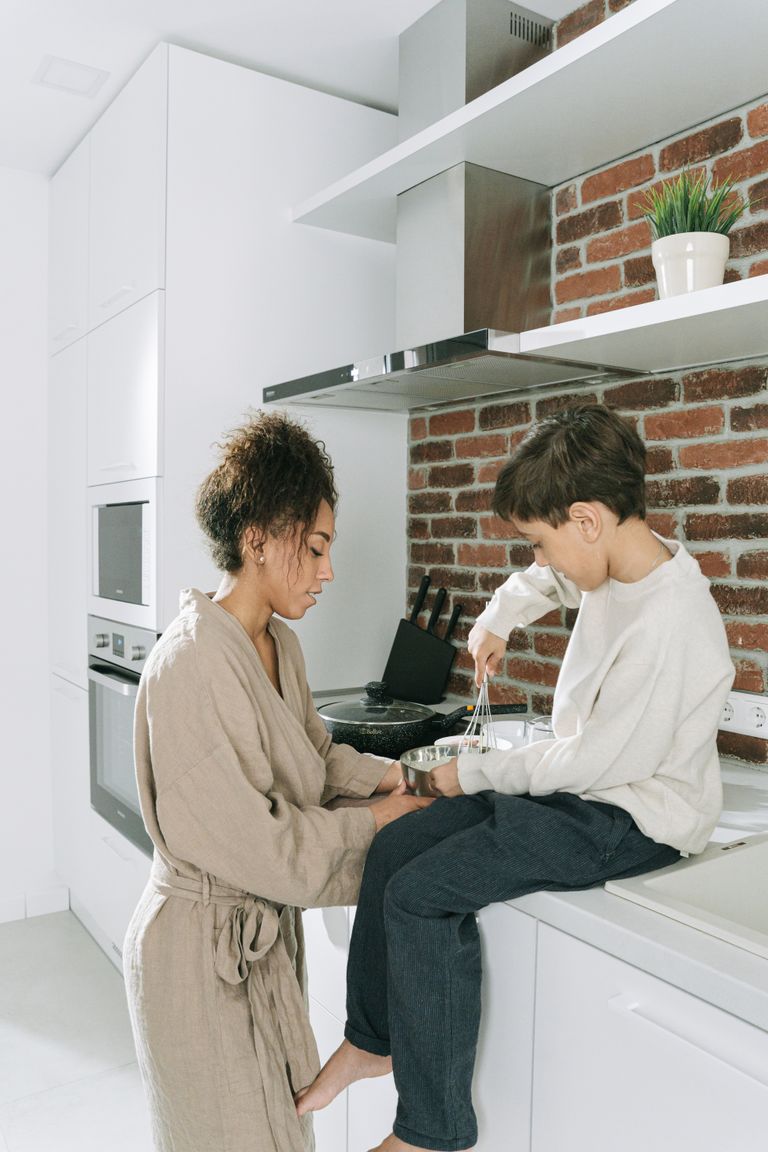 A mother and son enjoying quality time cooking in a contemporary kitchen setting.