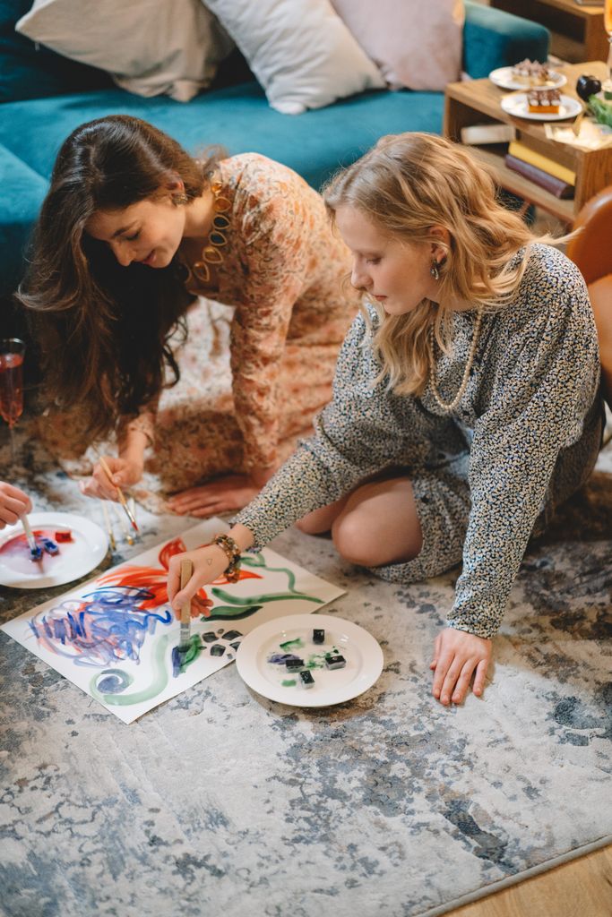 Two women enjoy a relaxing painting session on the living room floor.